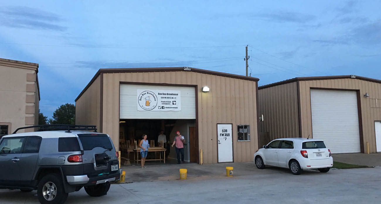 beer-chronicle-houston-craft-beer-review-featured-_0000_baa-baa-brewhouse-brookshire-parking-lot-and-brown-warehouse-buildings