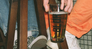 pint-glass-full-of-beer-held-low-next-to-sneakers-on-barstool-beer-chronicle-houston-best-beer-bars-to-visit-in-houston_0000_yasin-aribuga-daMT4OR3Eac-unsplash